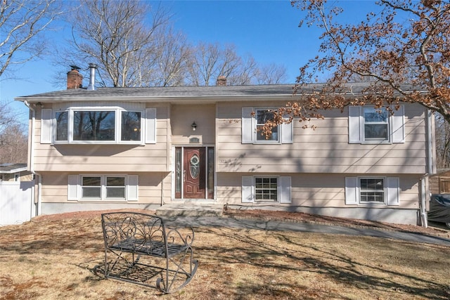 split foyer home featuring fence and a chimney