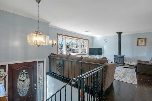 living area featuring dark wood-style floors, visible vents, a baseboard radiator, a wood stove, and crown molding