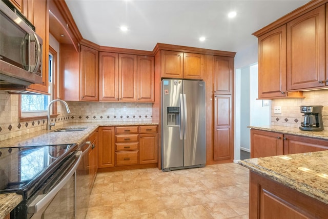 kitchen featuring stainless steel appliances, light stone countertops, and brown cabinets