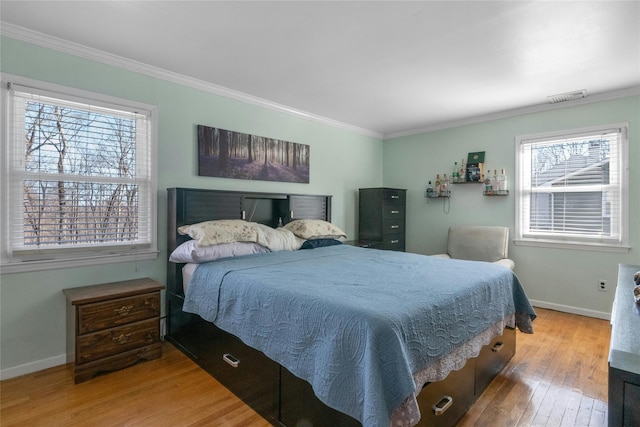 bedroom with hardwood / wood-style flooring, crown molding, visible vents, and baseboards