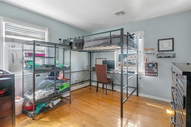 bedroom featuring multiple windows, wood finished floors, visible vents, and baseboards