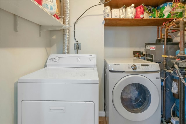 laundry area with laundry area, washing machine and dryer, and water heater