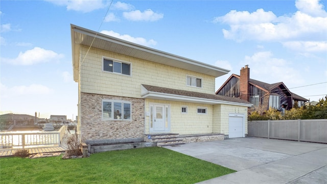 rear view of property featuring a garage, a lawn, fence, and concrete driveway