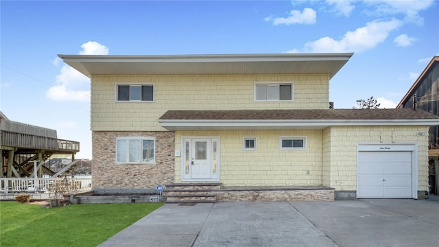 view of front of home featuring an attached garage, a front yard, concrete driveway, and roof with shingles