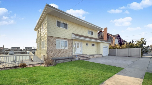 back of house with a lawn, fence, a garage, stone siding, and driveway