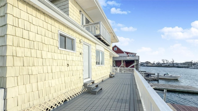 view of side of home featuring a water view, a boat dock, and a balcony