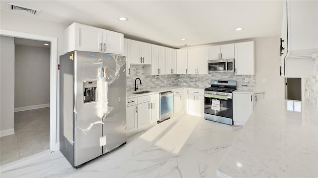 kitchen with stainless steel appliances, a sink, visible vents, and decorative backsplash