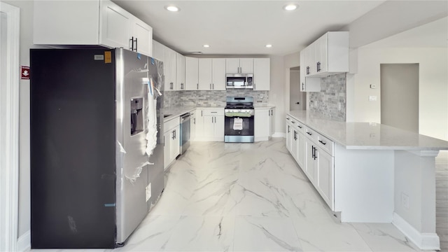 kitchen featuring marble finish floor, stainless steel appliances, a peninsula, and backsplash