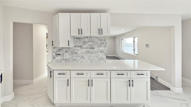 kitchen featuring baseboards, marble finish floor, tasteful backsplash, and white cabinets