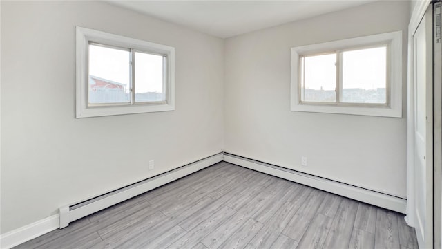 unfurnished room with a healthy amount of sunlight, light wood-style floors, a baseboard radiator, and baseboards