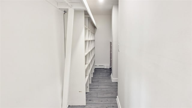 stairs featuring baseboards, a baseboard heating unit, and wood finished floors