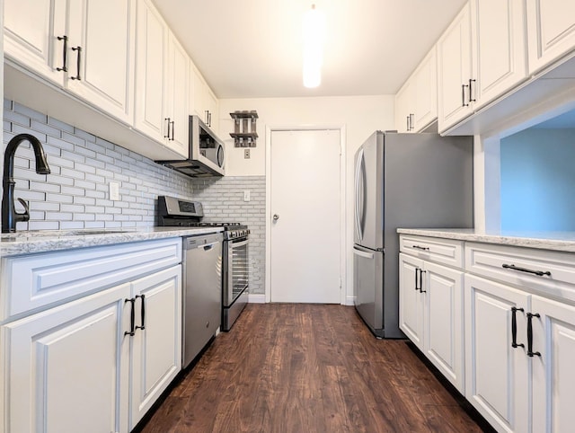 kitchen with dark wood-style flooring, a sink, white cabinets, appliances with stainless steel finishes, and decorative backsplash