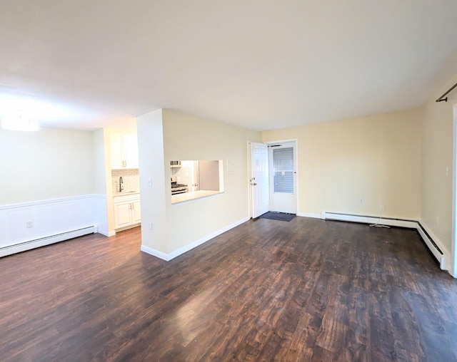 unfurnished room featuring a sink, baseboard heating, dark wood finished floors, and baseboards