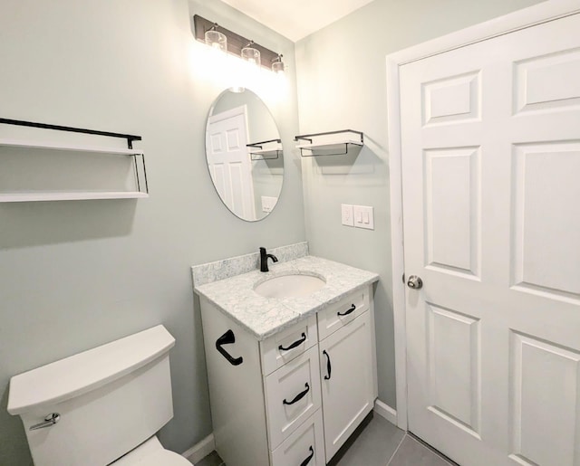 bathroom with toilet, vanity, and tile patterned floors