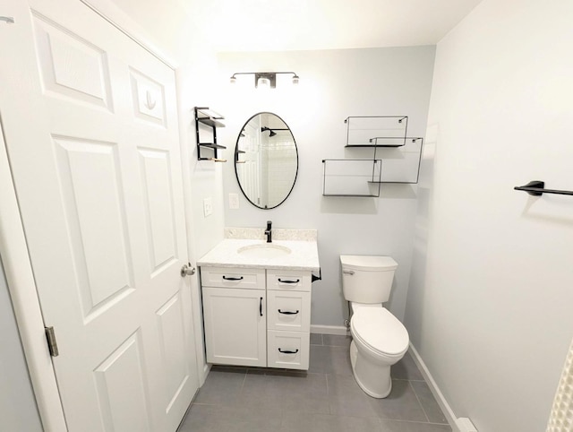 bathroom with tile patterned flooring, baseboards, vanity, and toilet