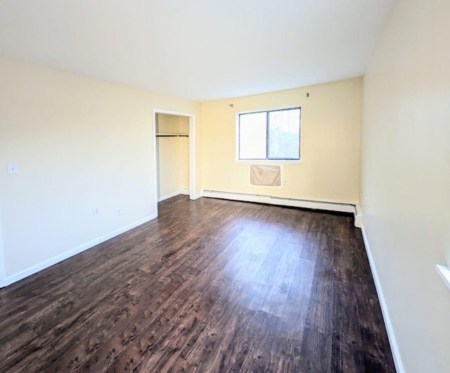 unfurnished bedroom with a baseboard heating unit, wood finished floors, and baseboards