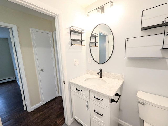 bathroom with baseboards, toilet, a baseboard radiator, wood finished floors, and vanity