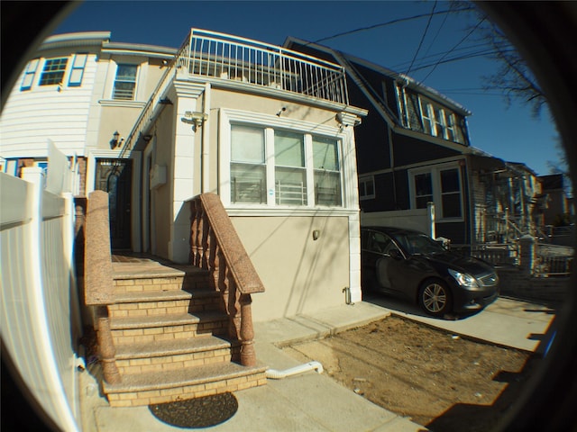 back of house with stucco siding and a balcony