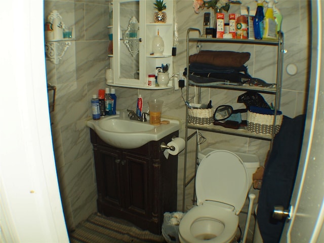 half bathroom featuring tasteful backsplash, toilet, tile walls, and vanity