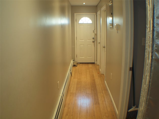 doorway featuring a baseboard heating unit, light wood-style flooring, and baseboards