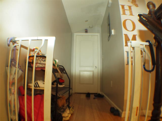 hall featuring hardwood / wood-style floors, lofted ceiling, and baseboards