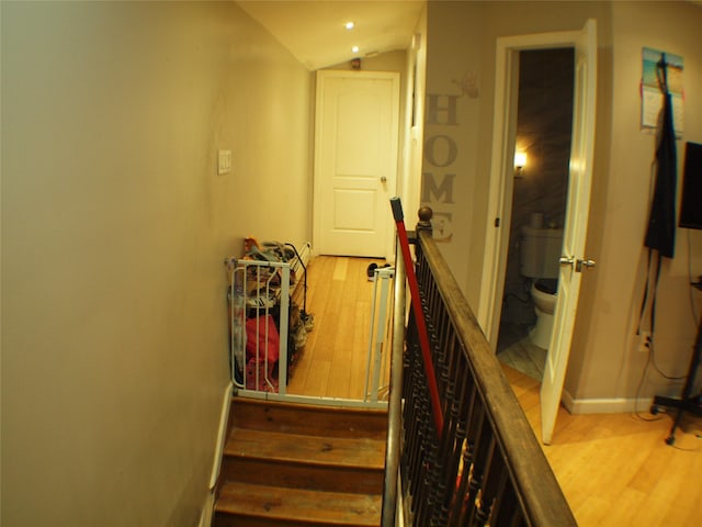 staircase with baseboards, lofted ceiling, and wood finished floors