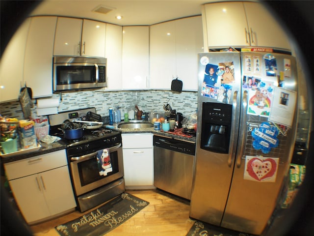 kitchen with tasteful backsplash, visible vents, light wood-type flooring, stainless steel appliances, and a sink