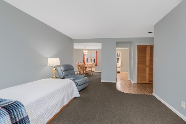 carpeted bedroom with a notable chandelier and baseboards