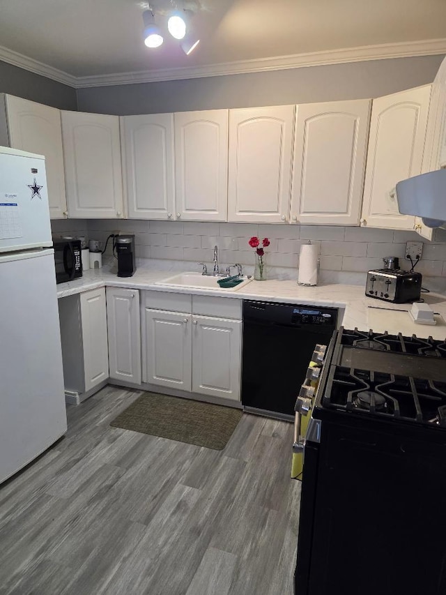 kitchen featuring ornamental molding, white cabinetry, a sink, wood finished floors, and black appliances