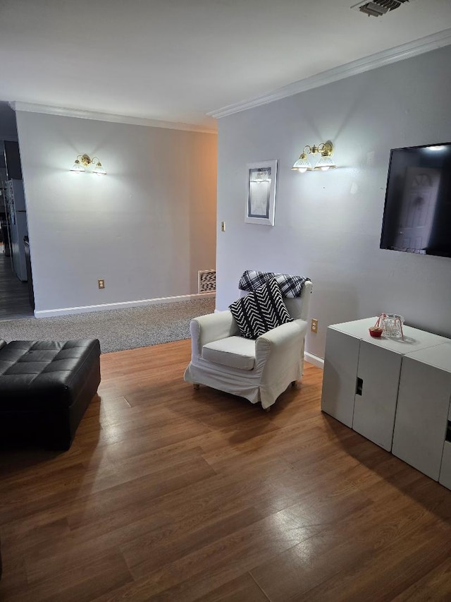 living area featuring visible vents, crown molding, baseboards, and wood finished floors