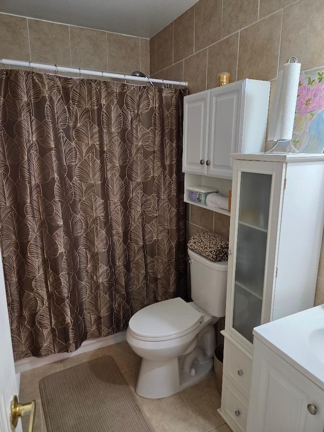 bathroom featuring curtained shower, toilet, tile walls, vanity, and tile patterned floors