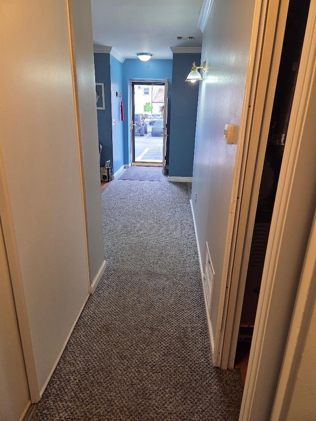 hallway featuring baseboards, carpet flooring, visible vents, and crown molding