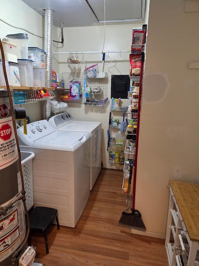 clothes washing area with wood finished floors, laundry area, washing machine and clothes dryer, and gas water heater