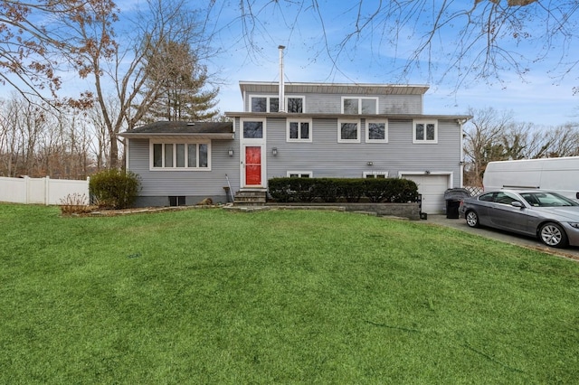 split level home featuring entry steps, an attached garage, fence, driveway, and a front yard