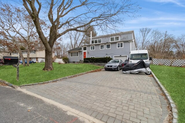 view of front facade with a garage, decorative driveway, a front yard, and fence