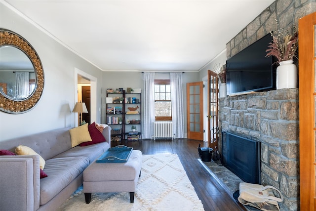 living room with crown molding, radiator heating unit, a fireplace, and wood-type flooring