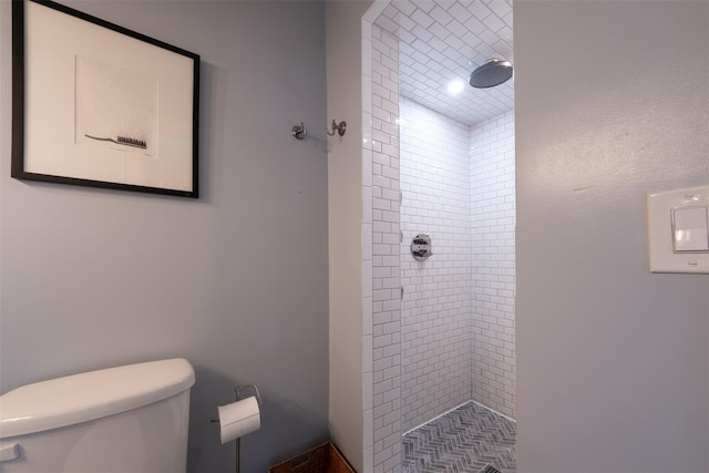 bathroom featuring a tile shower and toilet