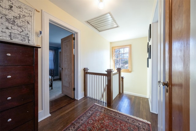 hallway with baseboards, an upstairs landing, and dark wood-style floors