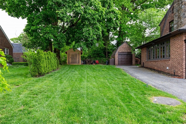 view of yard with an outbuilding, a garage, and aphalt driveway