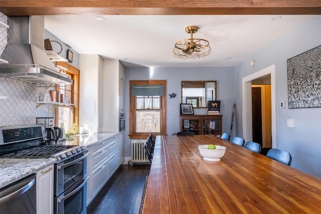 kitchen with tasteful backsplash, radiator heating unit, light stone counters, appliances with stainless steel finishes, and island exhaust hood