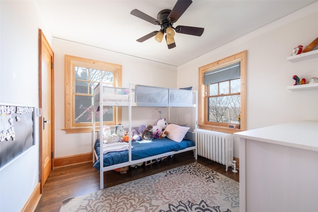 bedroom with baseboards, multiple windows, wood finished floors, and radiator heating unit