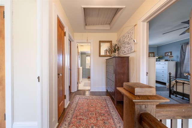 hallway with attic access, baseboards, and wood finished floors