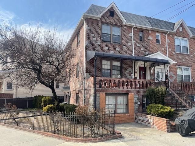 townhome / multi-family property with a fenced front yard, brick siding, and a shingled roof