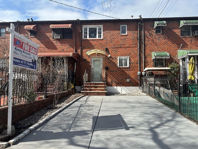 back of house with entry steps, brick siding, and fence