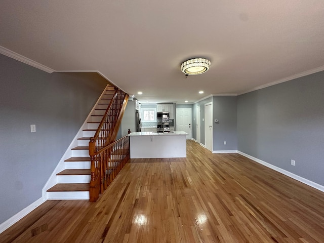 unfurnished living room featuring baseboards, ornamental molding, wood finished floors, stairs, and recessed lighting