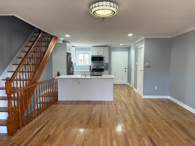 kitchen featuring a peninsula, light wood-type flooring, ornamental molding, and stainless steel appliances