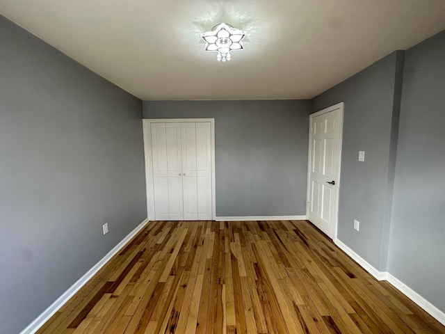 unfurnished bedroom with a closet, wood-type flooring, and baseboards