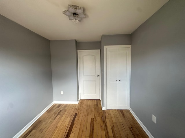 unfurnished bedroom featuring a closet, baseboards, and hardwood / wood-style floors