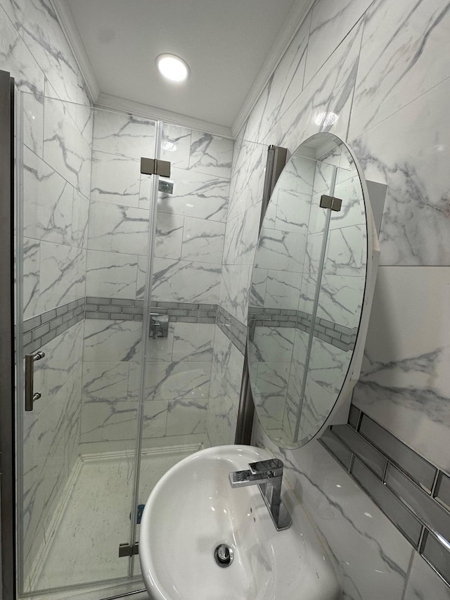 bathroom featuring a sink, a marble finish shower, and crown molding