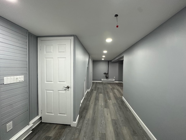 hall featuring dark wood-style floors, wooden walls, and baseboards